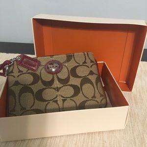 Coach small wristlet in brown signature logo with burgundy trim.